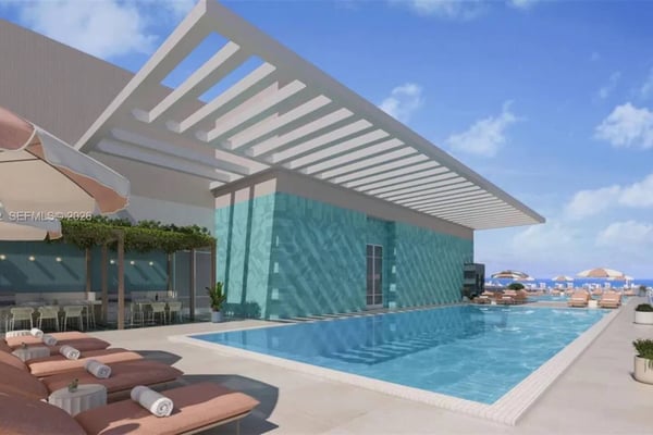 Backyard with curved swimming pool, lounge chairs, patio, and single-story house with wooden fence under blue sky